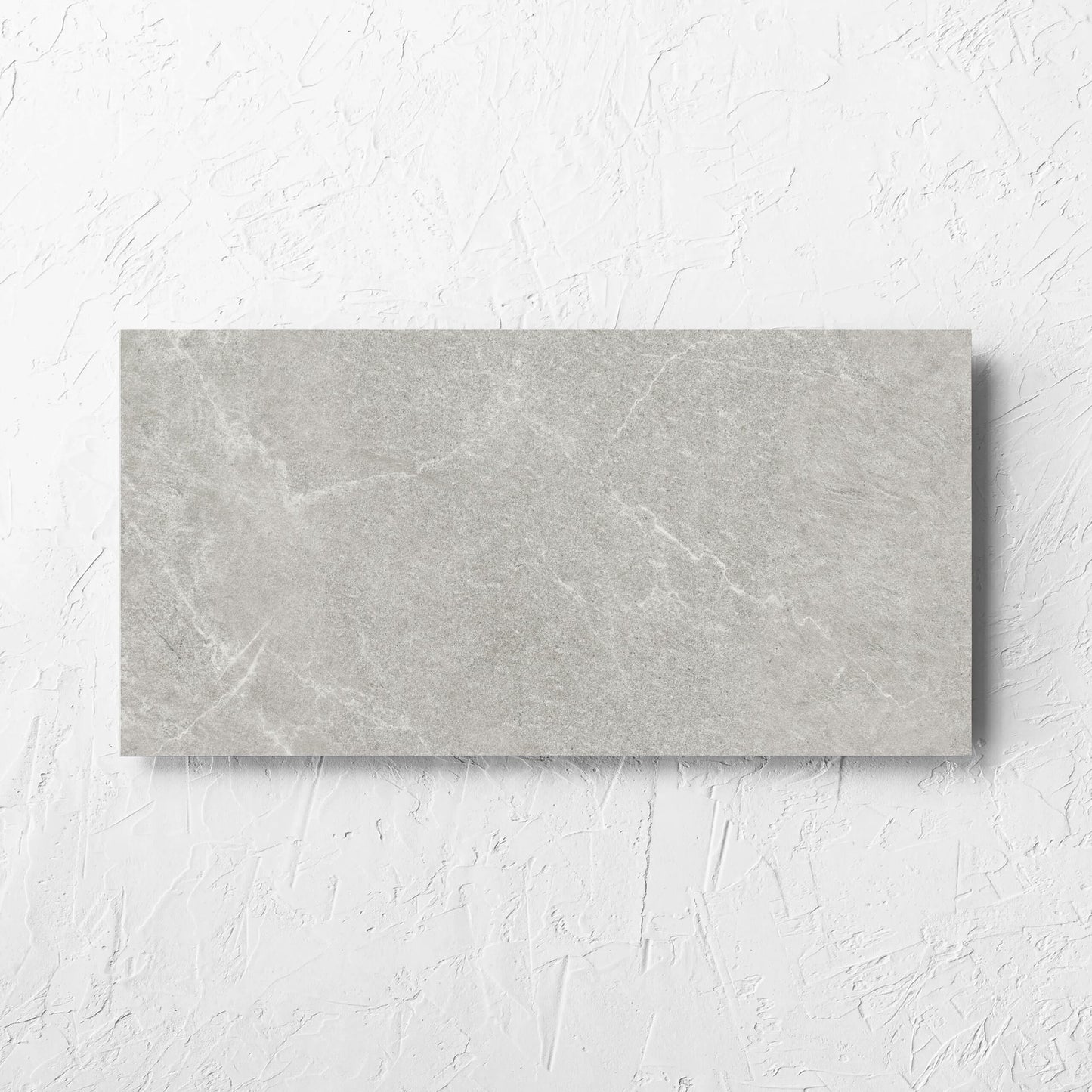 Lava Ash Amber 300x600mm tile laid flat on a white rendered wall, showing the ash matt surface