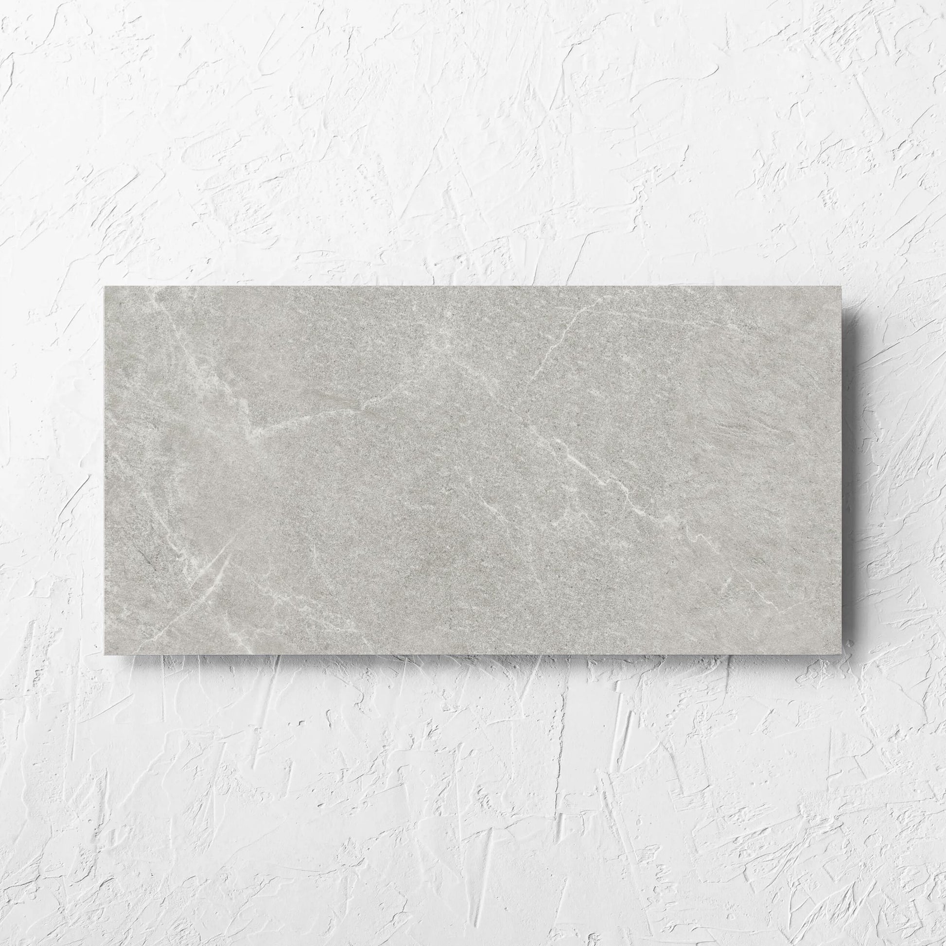 Lava Ash Amber 300x600mm tile laid flat on a white rendered wall, showing the ash matt surface