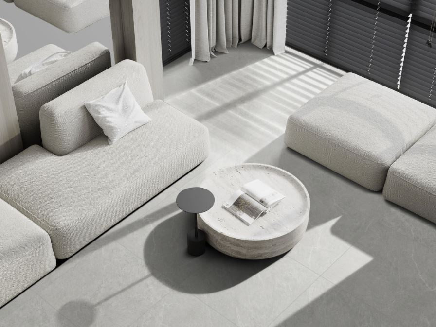 Lava Ash Amber 300x600mm porcelain floor tiles in a minimalist living room with light grey modular sofa and round travertine coffee table.