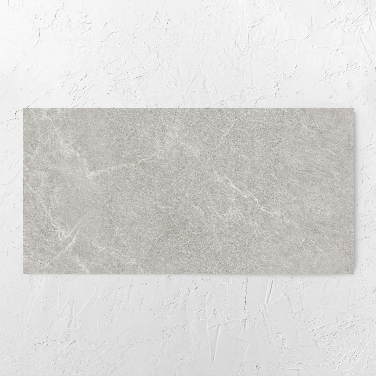 Lava Ash Amber 600x1200mm tile laid flat on a white rendered wall, showing the ash surface