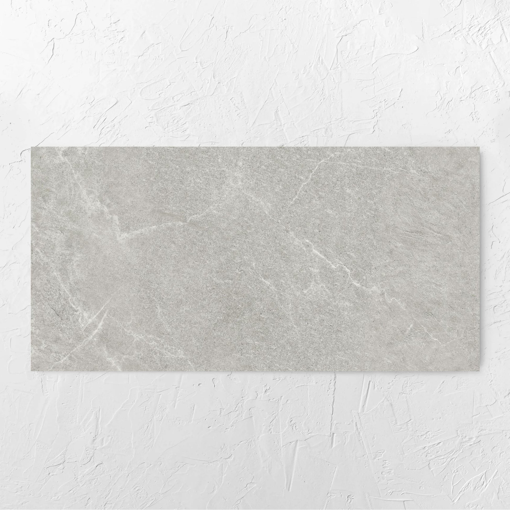 Lava Ash Amber 600x1200mm tile laid flat on a white rendered wall, showing the ash surface