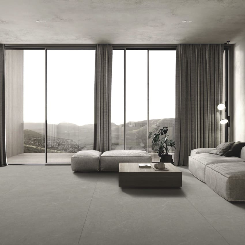 Lava Ash Amber 600x1200mm large-format grey tiles installed as a living room floor in a minimalist space with floor-to-ceiling windows and modular sofa.