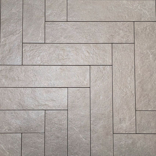 Lava Ash Amber Brick/Subway 75x300mm tiles arranged in a herringbone pattern, showcasing a textured grey stone-effect finish with fine grout lines.
