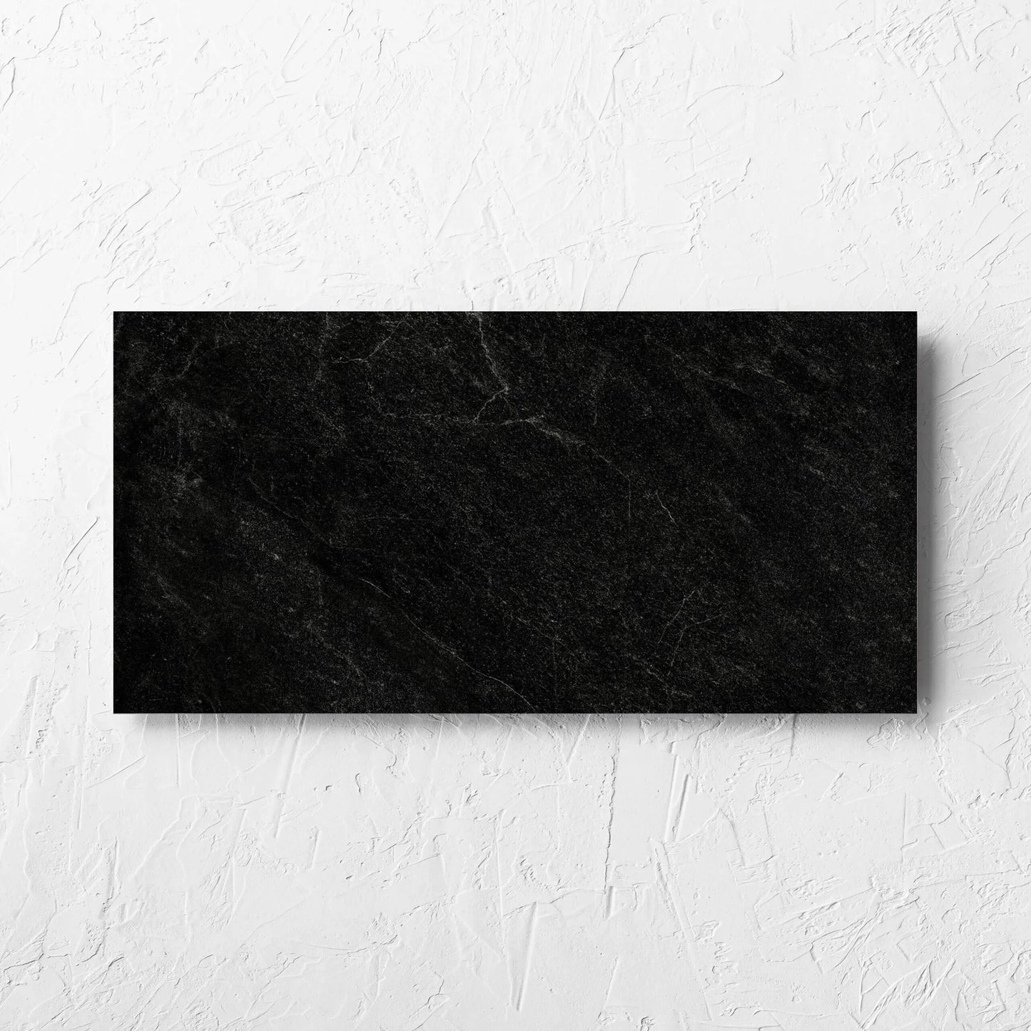 Lava Black Amber 300x600mm tile laid flat on a white rendered wall, showing the lappato surface