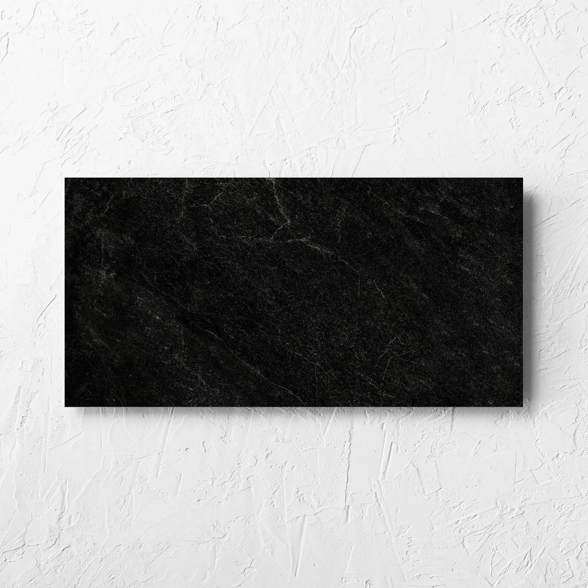 Lava Black Amber 300x600mm tile laid flat on a white rendered wall, showing the lappato surface