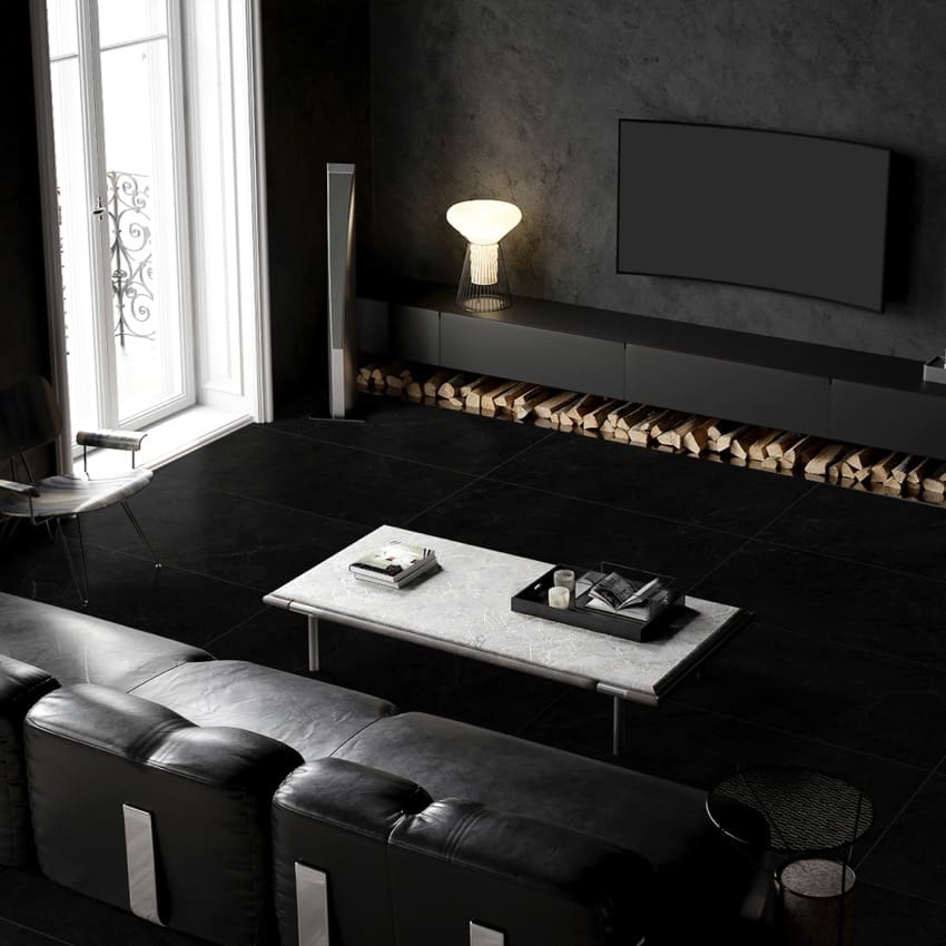 Lava Black Amber 300x600mm matte black tiles installed on a living room floor with dark leather sofas, marble coffee table, and wall-mounted TV.