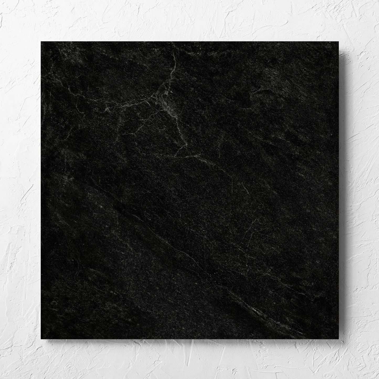 Lava Black Rect Inout 600x600mm tile laid flat on a white rendered wall, showing the tile surface