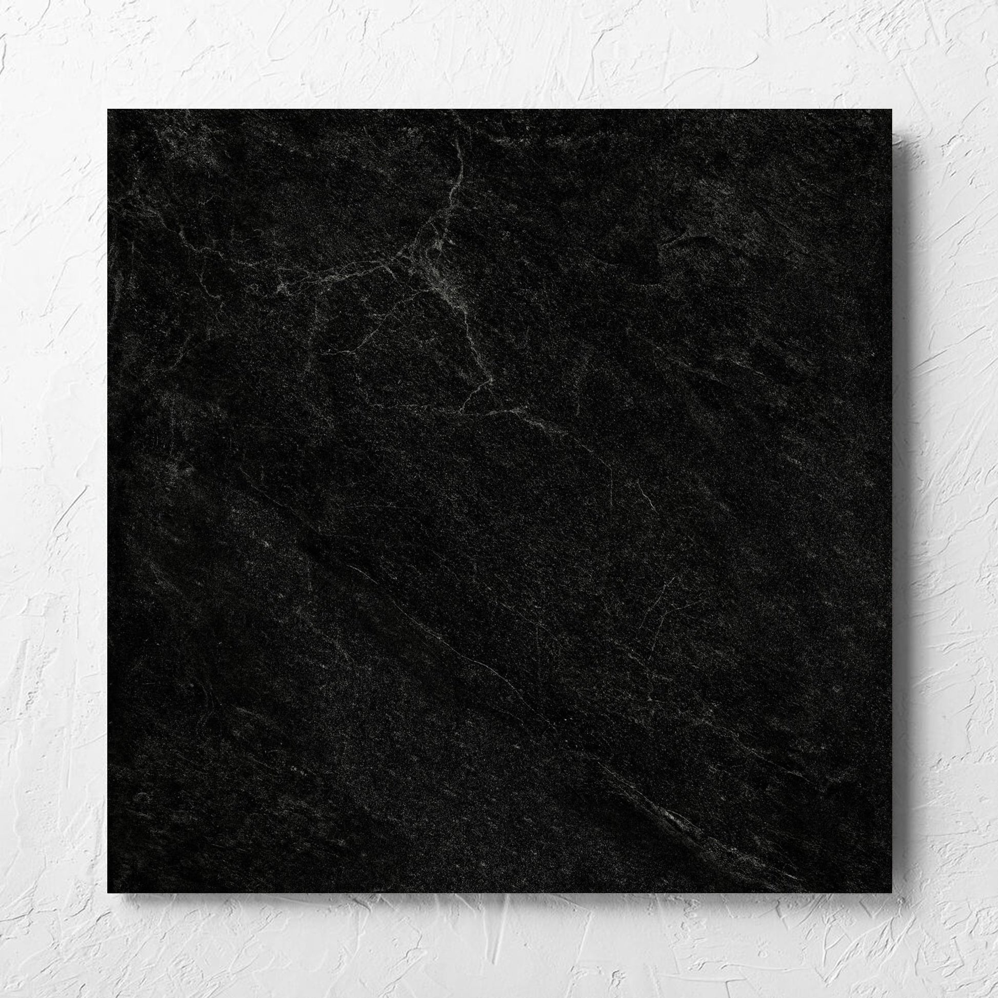 Lava Black Rect Inout 600x600mm tile laid flat on a white rendered wall, showing the tile surface