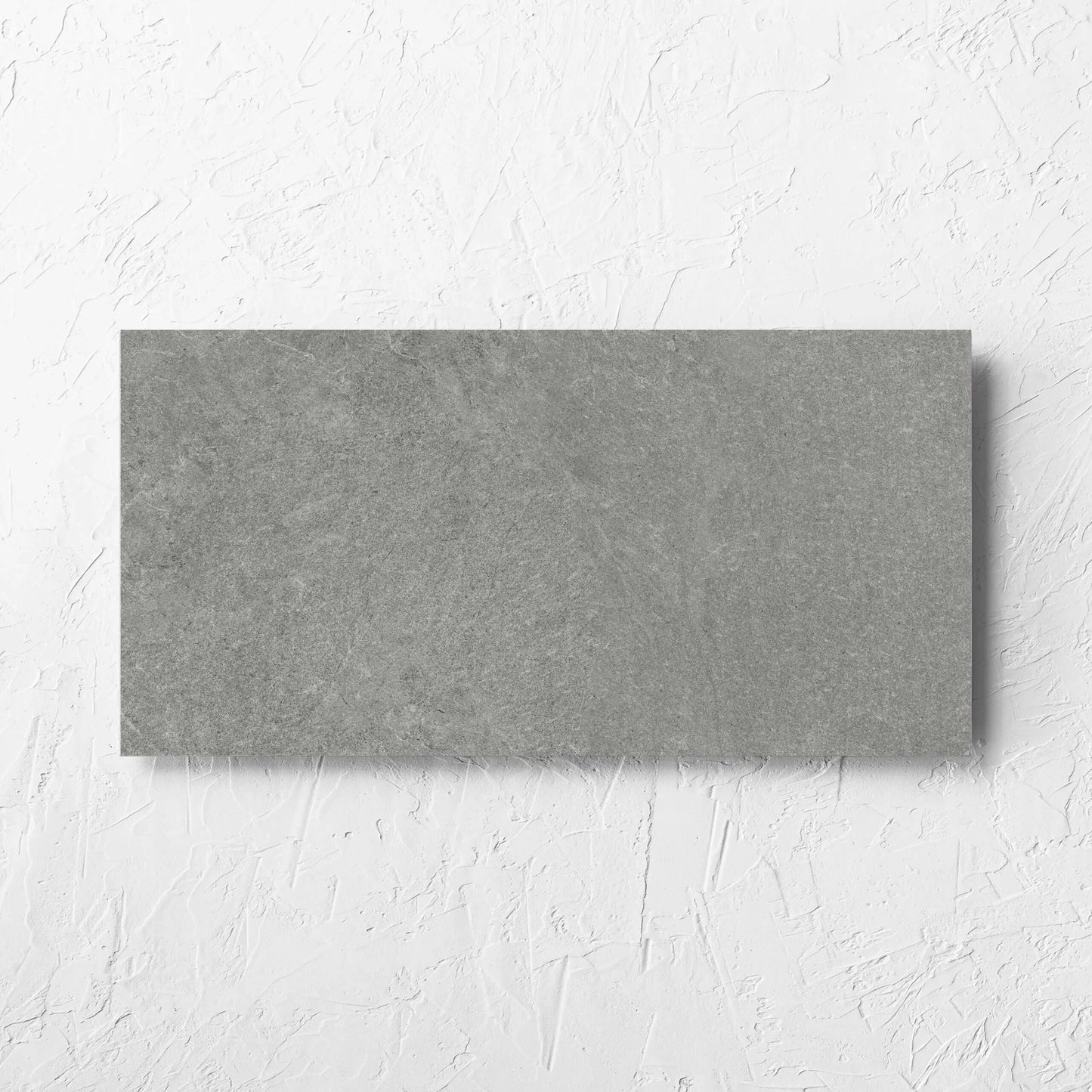 Lava Grey Amber 300x600mm tile laid flat on a white rendered wall, showing the lappato surface