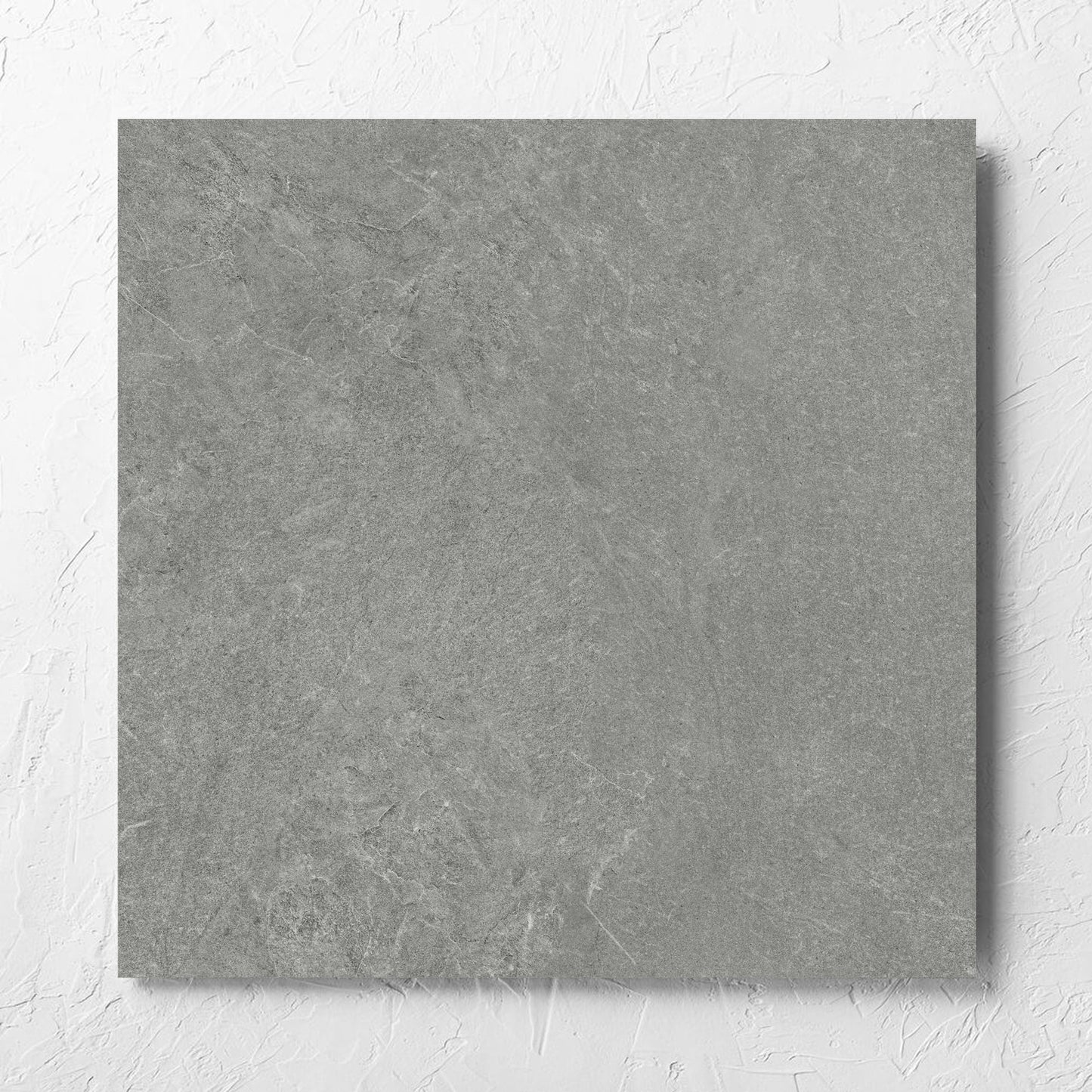 Lava Grey Amber 600x600mm tile laid flat on a white rendered wall, showing the grey lappato surface