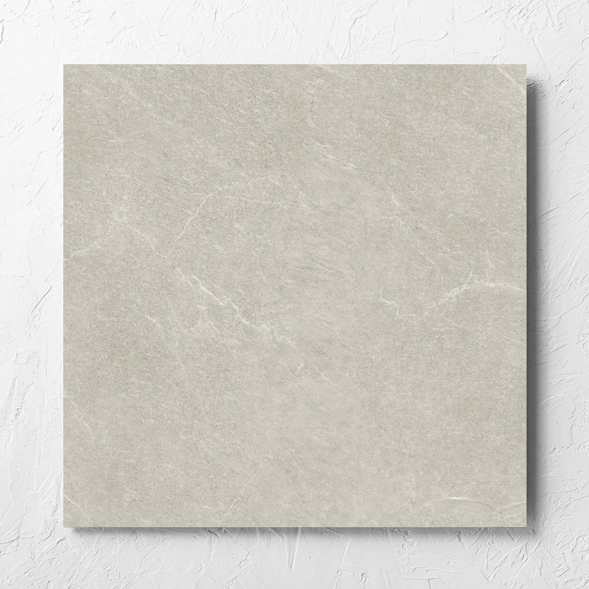 Lava Soft Beige Amber 600x600mm tile laid flat on a white rendered wall, showing the soft beige lappato surface