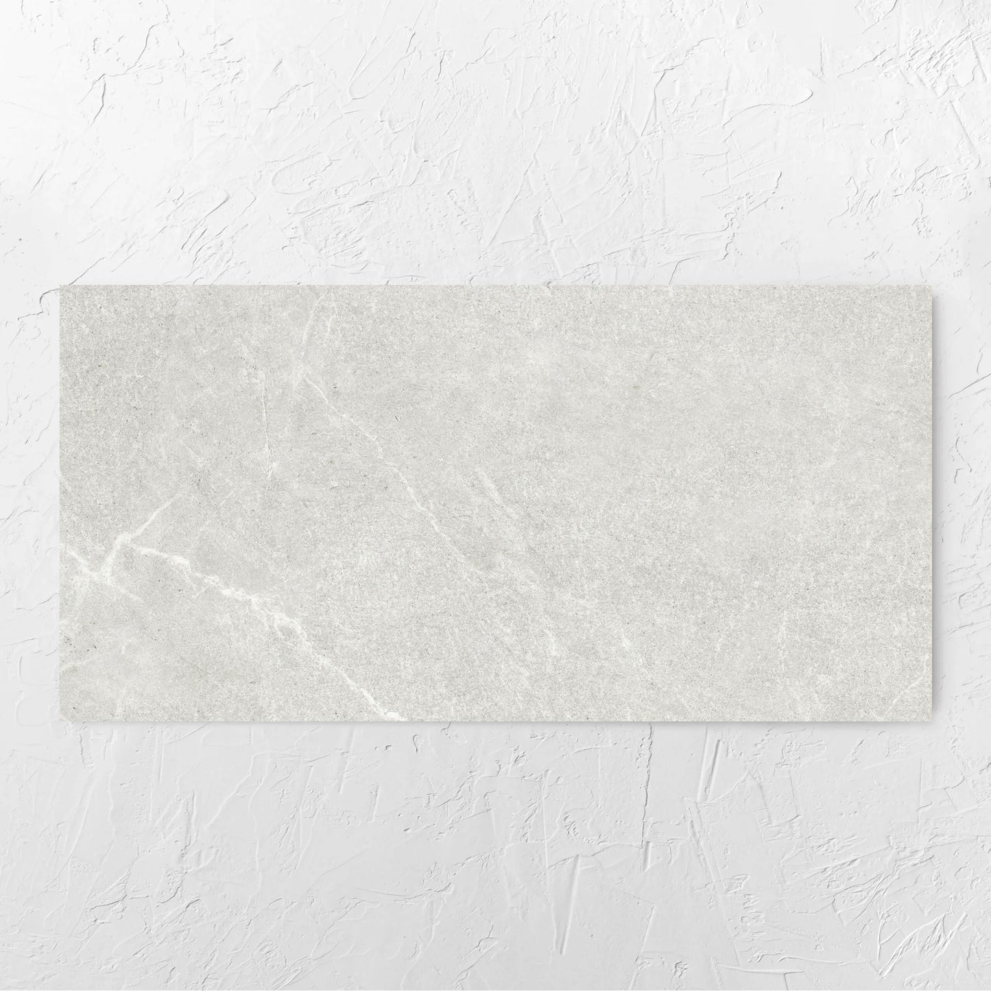 Lava Warm Grey Amber 600x1200mm tile laid flat on a white rendered wall, showing the warm grey surface