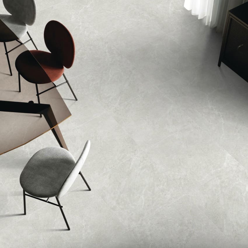 Lava Warm Grey Amber 600x1200mm porcelain tiles installed as a polished light grey floor in a modern living space with designer chairs and a dining table.