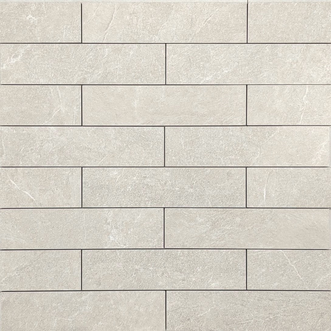 Flat lay of Lava Warm Grey Amber Brick/Subway 75x300mm tiles showing a staggered brick pattern with a matte stone finish in soft warm grey tones.