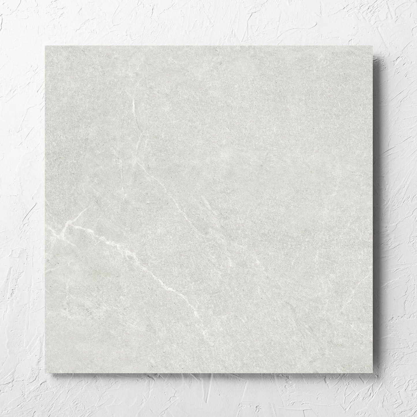 Lava Warm Grey Inout 600x600mm tile laid flat on a white rendered wall, showing the tile surface