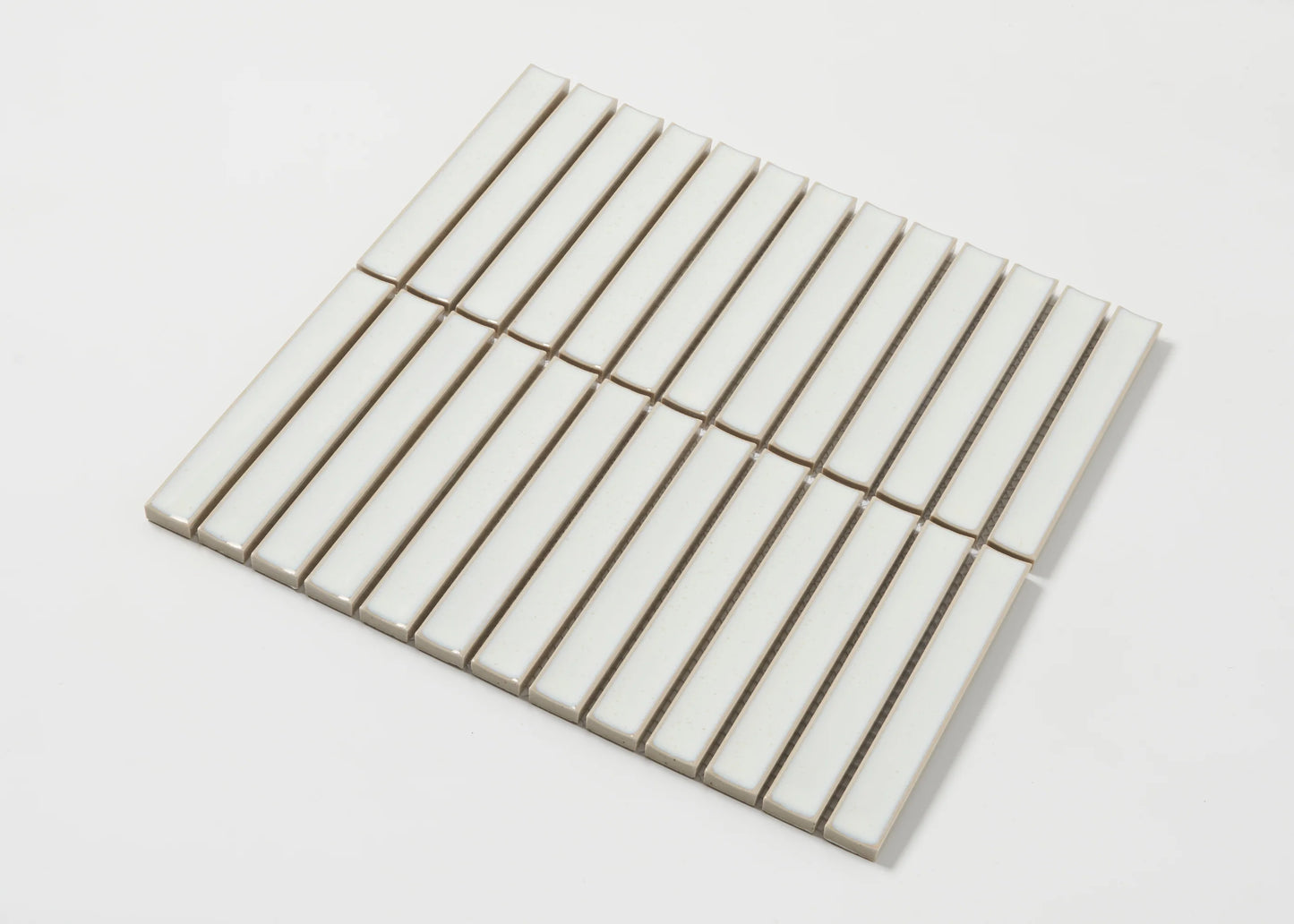 Pack shot of Linen Speckled Gloss Concave Porcelain Glazed Finger 20x145mm tiles arranged in a flat grid showing their elongated rectangular shape and creamy white gloss finish.
