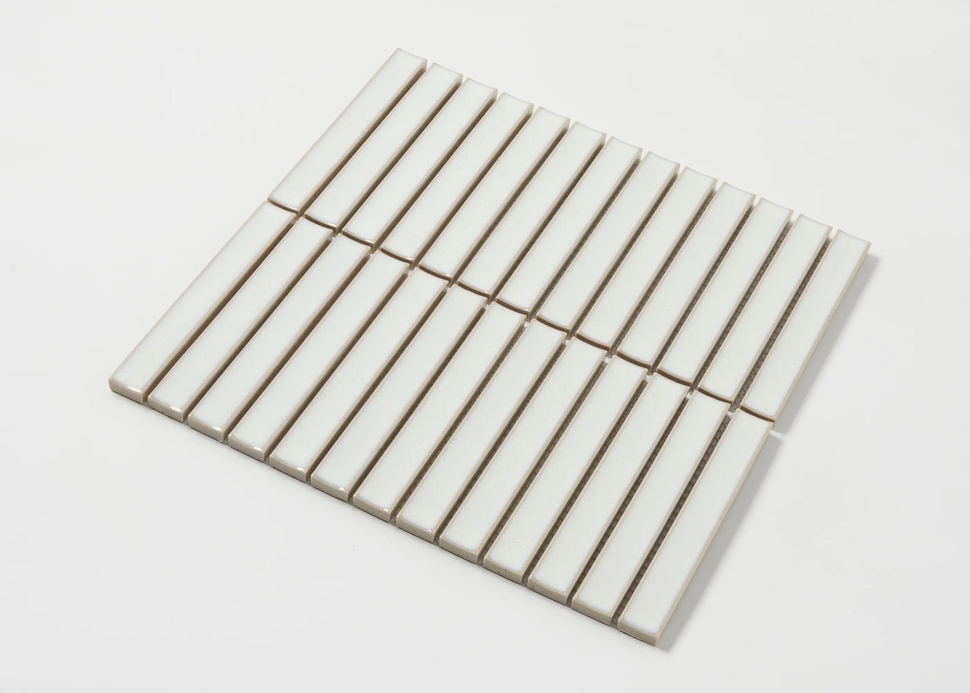 Pack shot of Linen Speckled Gloss Concave Porcelain Glazed Finger 20x145mm tiles arranged in a flat grid showing their elongated rectangular shape and creamy white gloss finish.