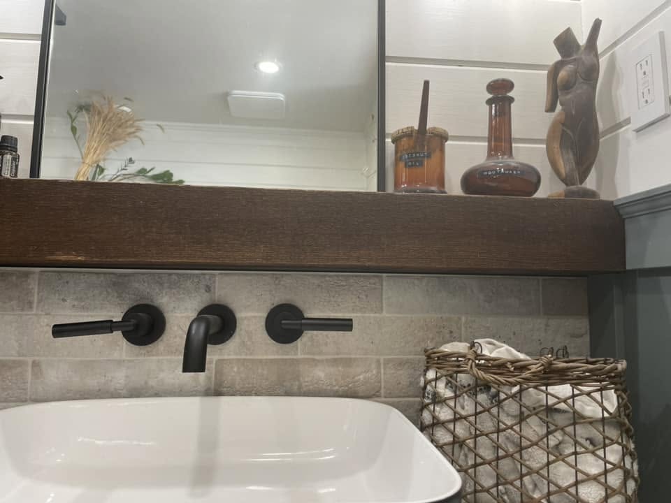 London Fog Brick Tile 60x250mm installed as a bathroom vanity splashback with matte black wall-mount faucets, a timber floating shelf, and white vessel sink.