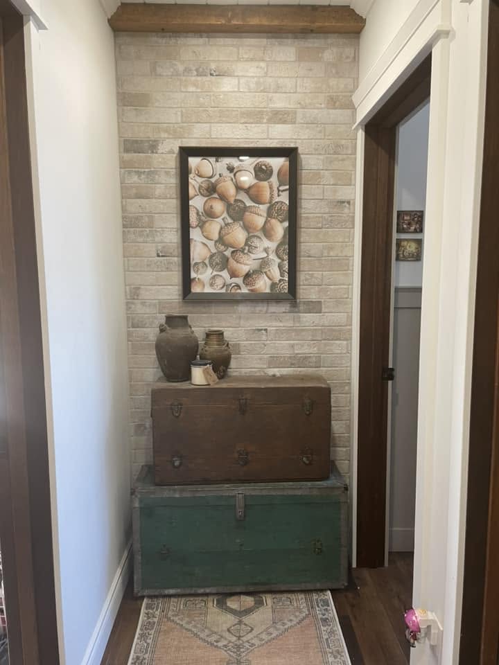 London Fog Brick Tile 60x250mm installed as a warm cream hallway feature wall styled with stacked vintage trunks and rustic ceramic vessels.