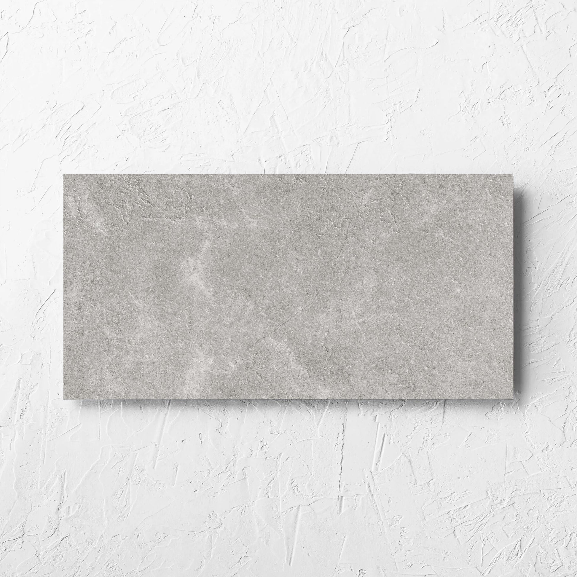 Lusso Grigio Matt 300x600mm tile laid flat on a white rendered wall, showing the matt surface