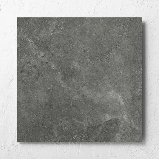 Lusso Midnight Amber 600x600mm tile laid flat on a white rendered wall, showing the matt surface
