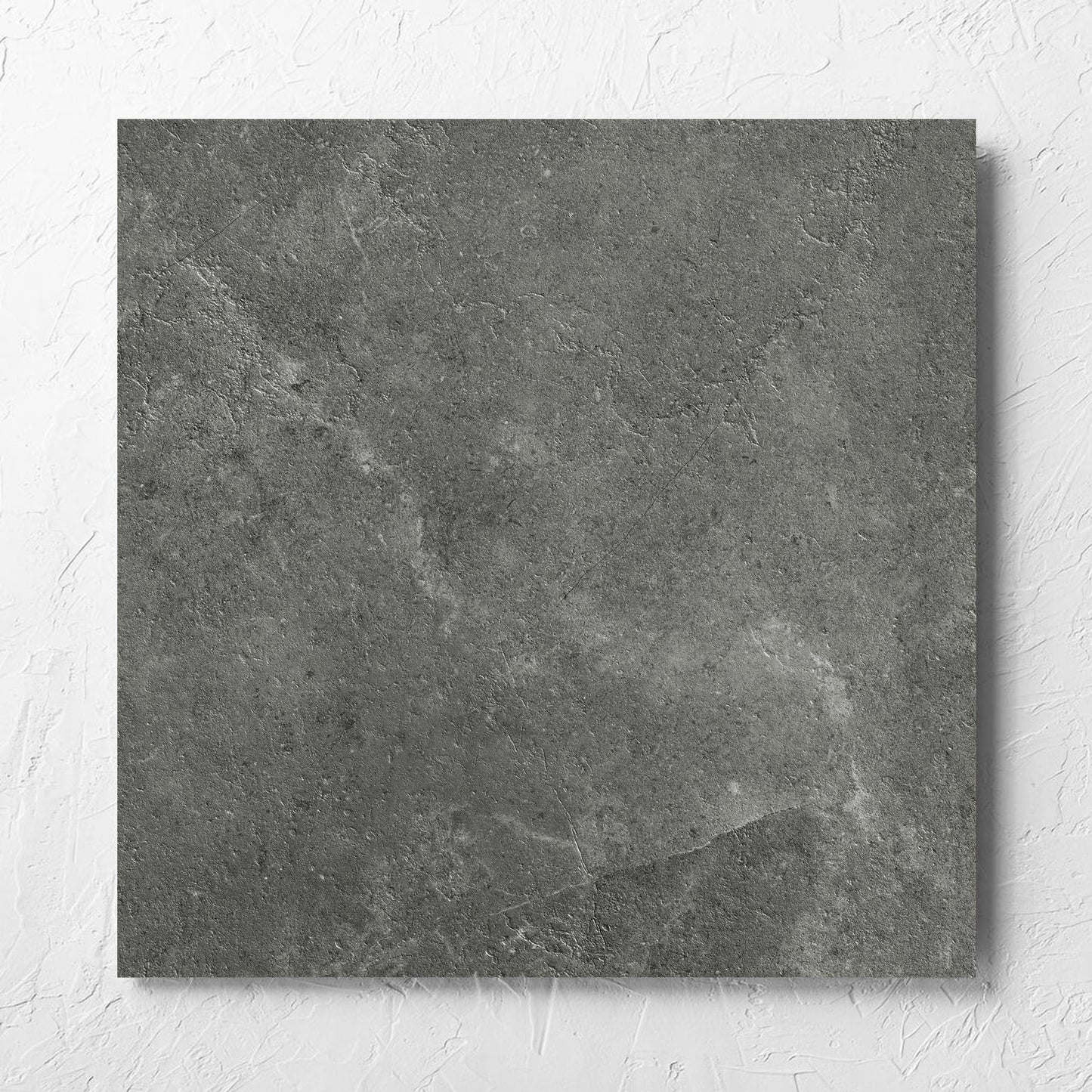 Lusso Midnight Matt 600x600mm tile laid flat on a white rendered wall, showing the matt surface