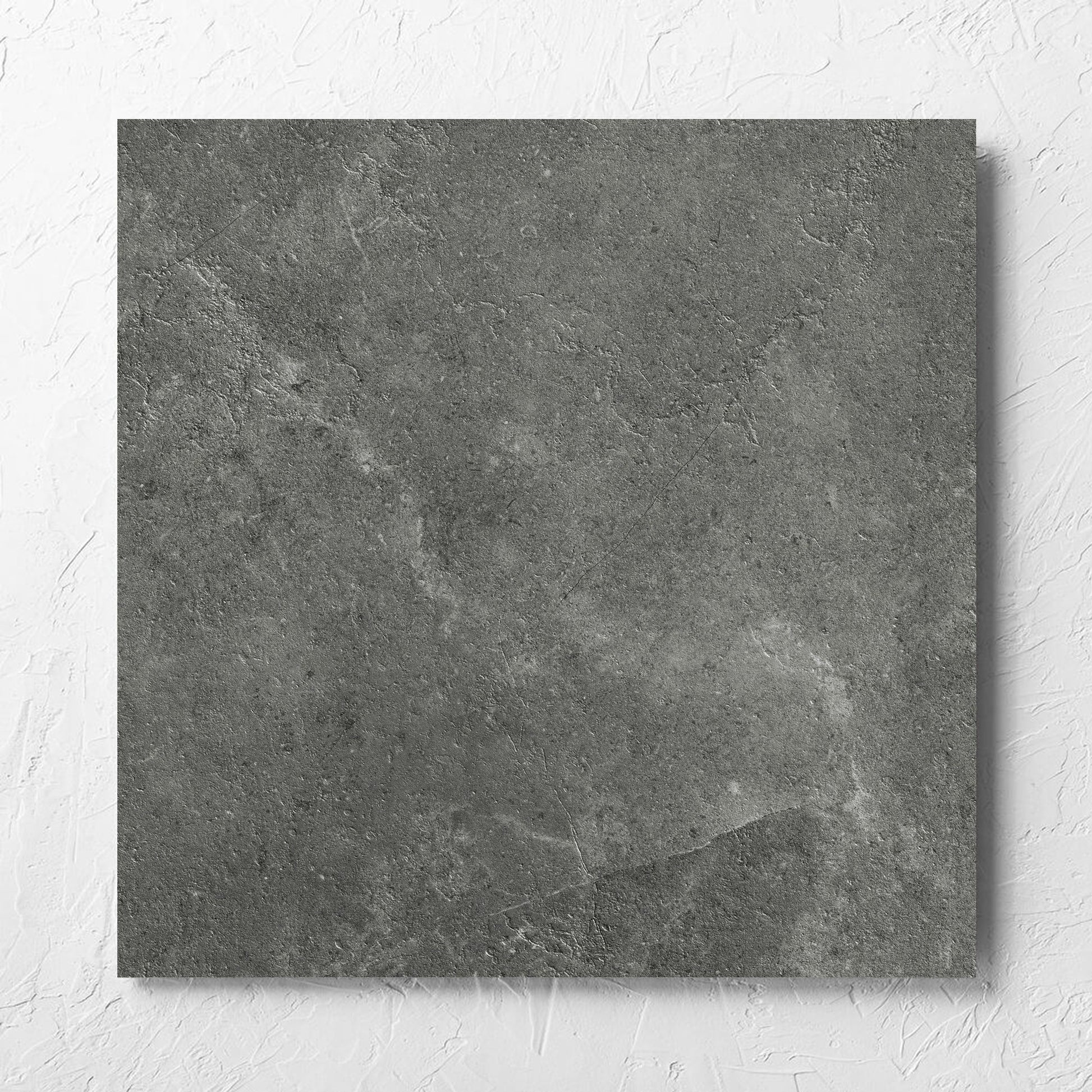 Lusso Midnight Matt 600x600mm tile laid flat on a white rendered wall, showing the matt surface