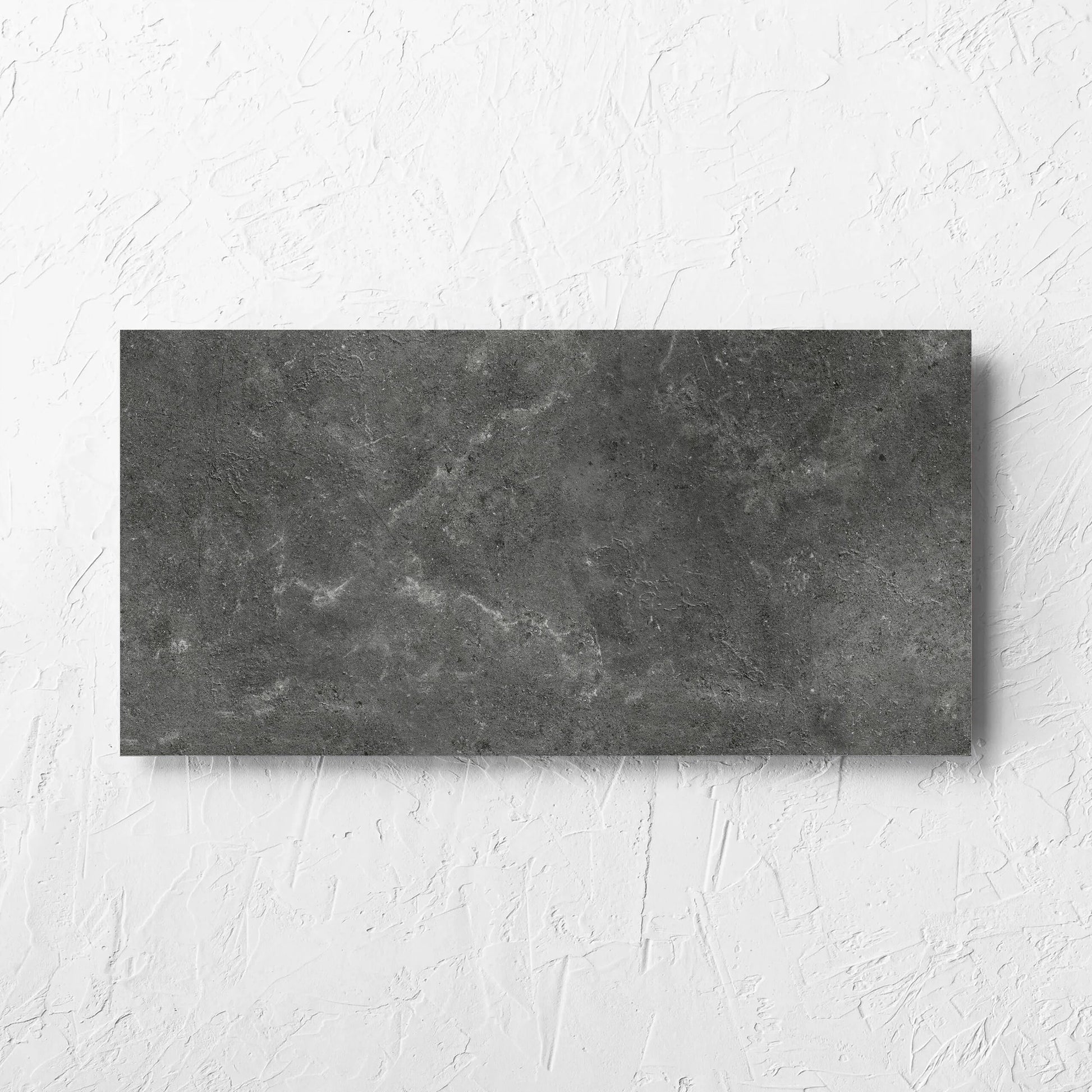 Lusso Nero Amber 300x600mm tile laid flat on a white rendered wall, showing the matt surface