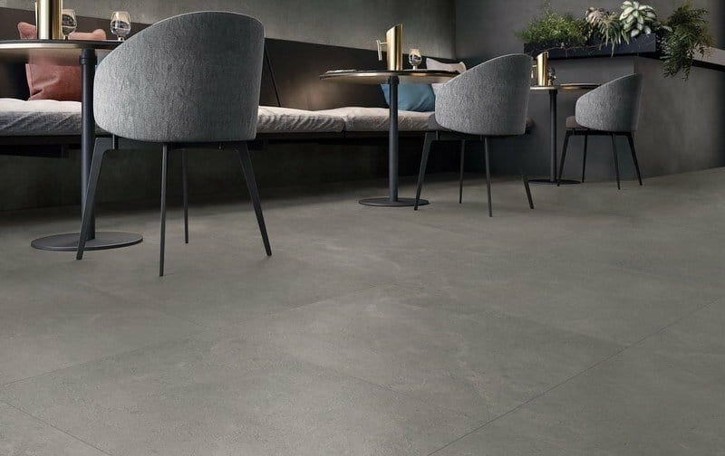Lusso Nero Matt 600x600mm dark grey porcelain floor tiles installed in a modern cafe seating area with upholstered chairs and bistro tables.