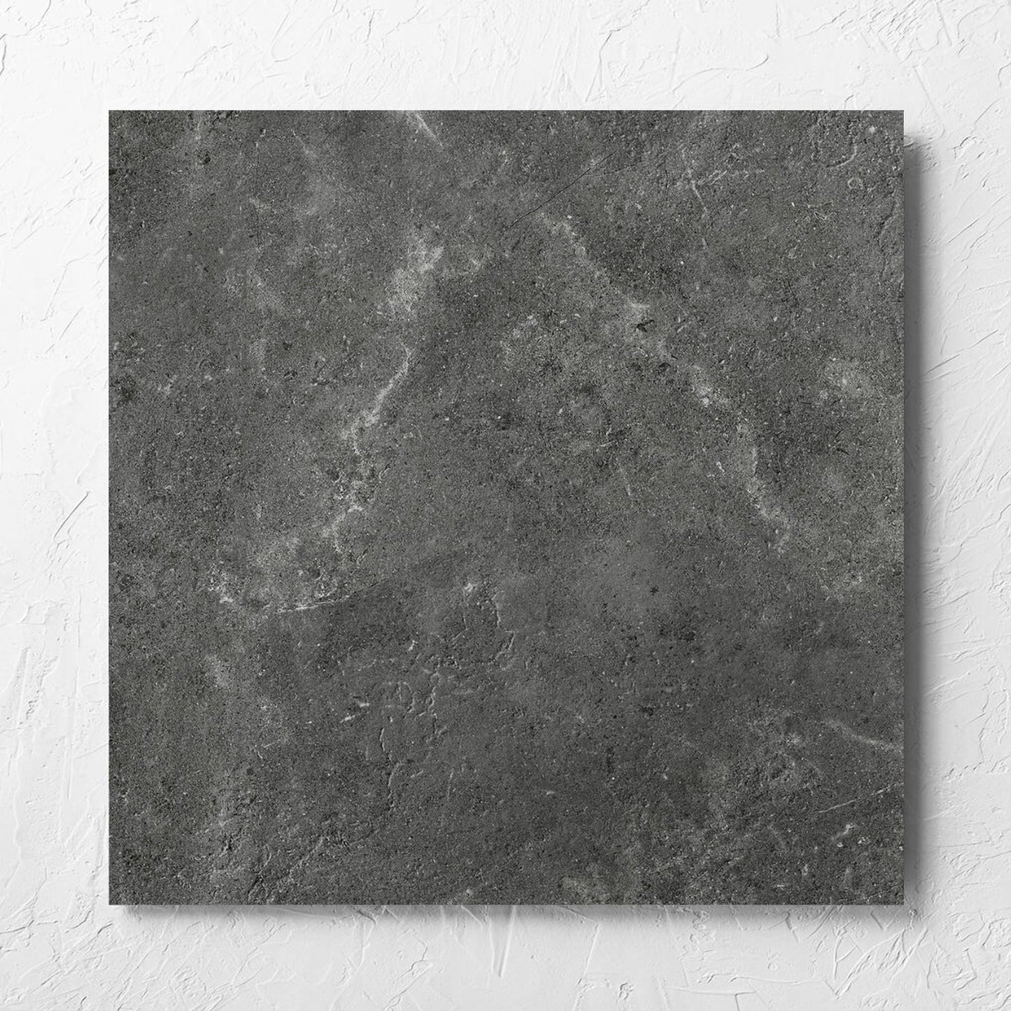 Lusso Nero Matt 600x600mm tile laid flat on a white rendered wall, showing the matt surface