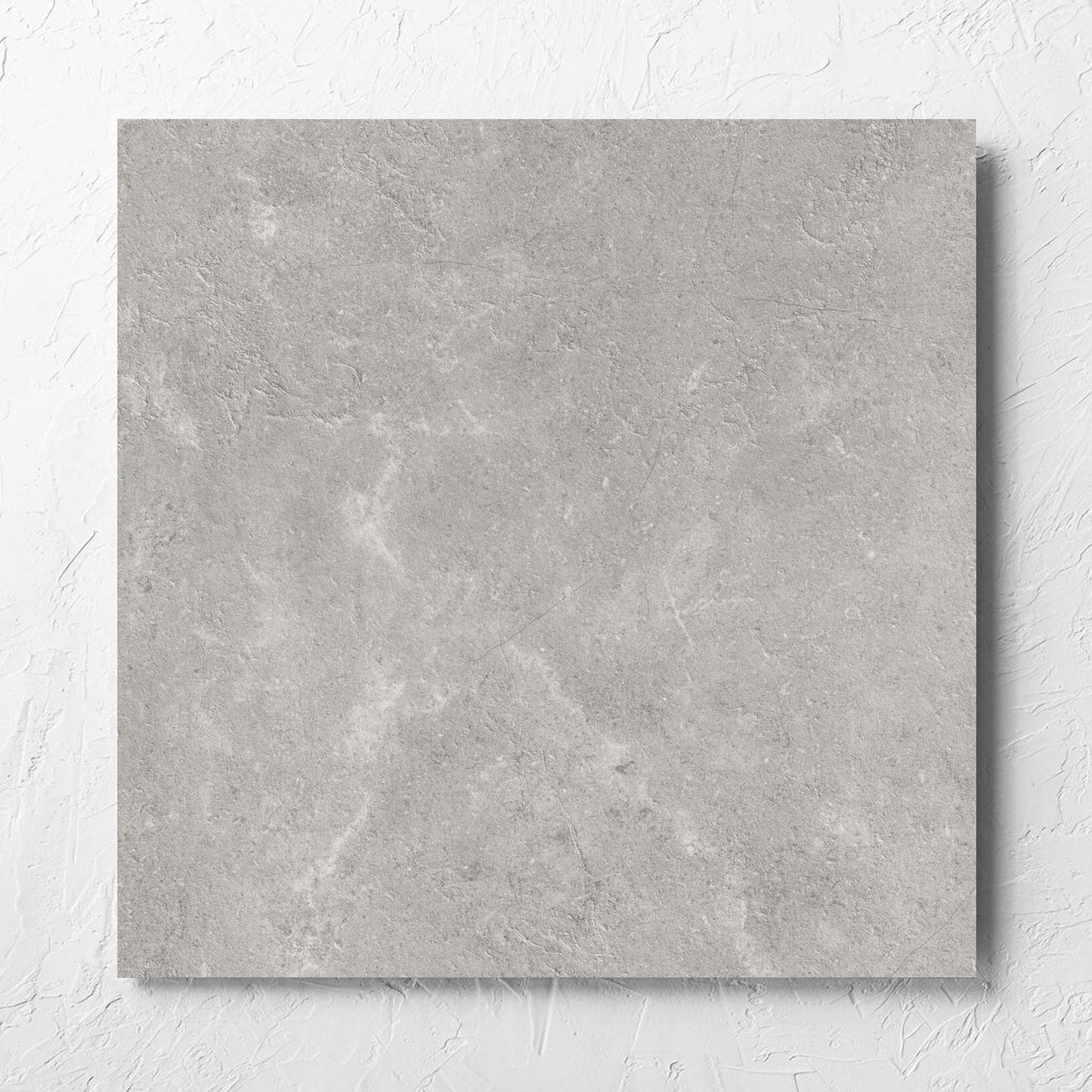 Lusso Terra Amber 600x600mm tile laid flat on a white rendered wall, showing the matt surface