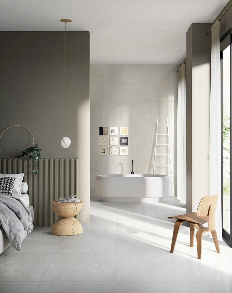 Lusso Terra Matt 600x600mm light grey floor and wall tiles in an open-plan bedroom suite featuring a freestanding bath and pendant light.