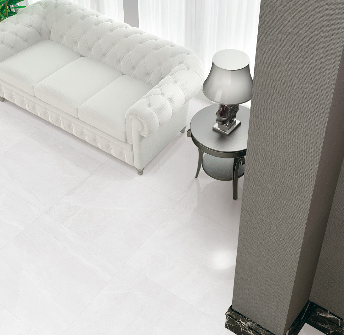 Mainstream White Polished 600x600mm floor tiles installed in an elegant living room with a white tufted Chesterfield sofa and silver table lamp.