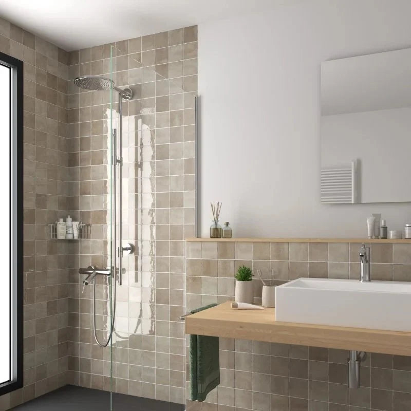 Majorca Gloss Taupe 100x100mm tiles installed in a modern bathroom featuring a walk-in shower and wooden vanity unit.