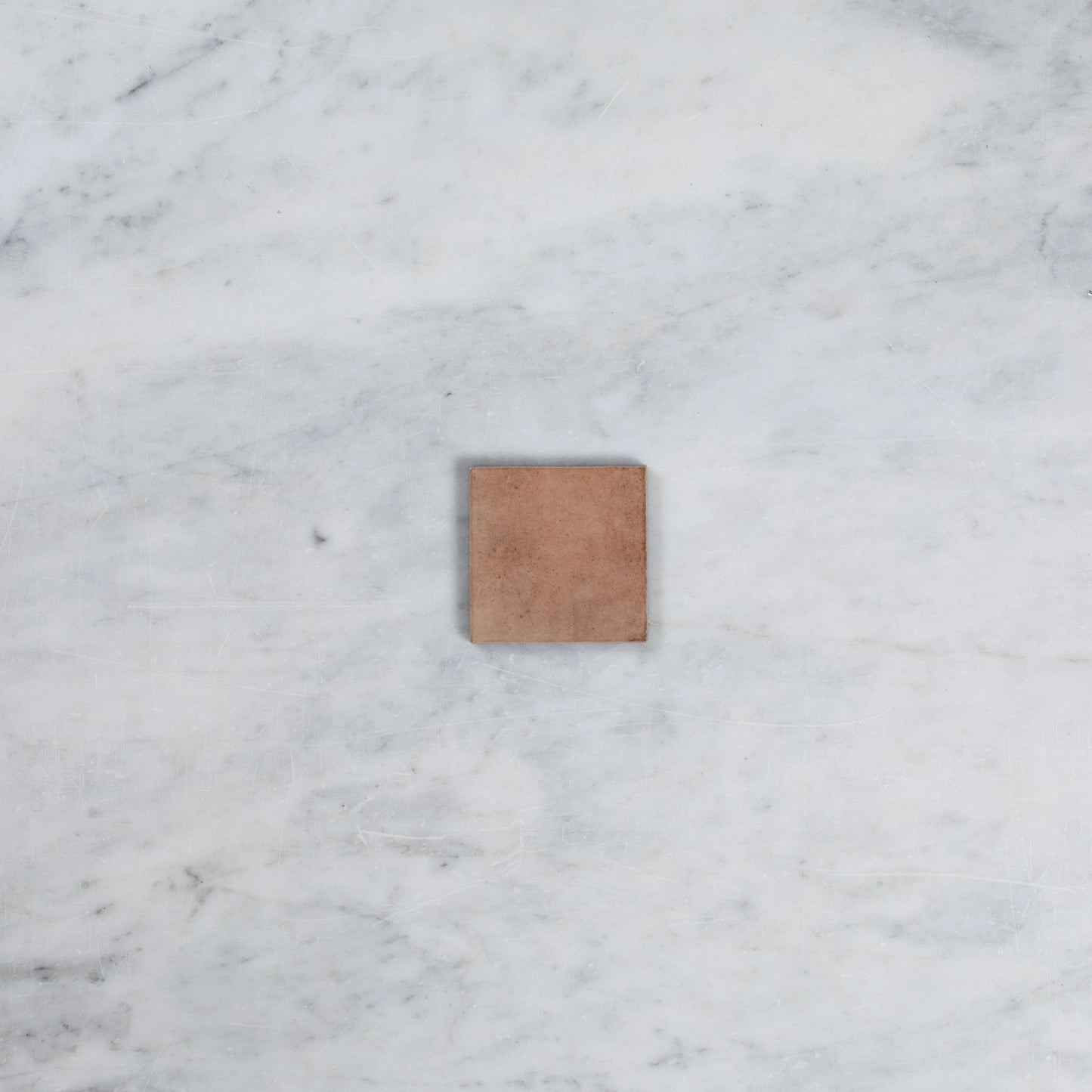 A single Majorca Matt Cotto 100x100mm square tile sample displaying a warm terracotta matt finish on a white marble surface.