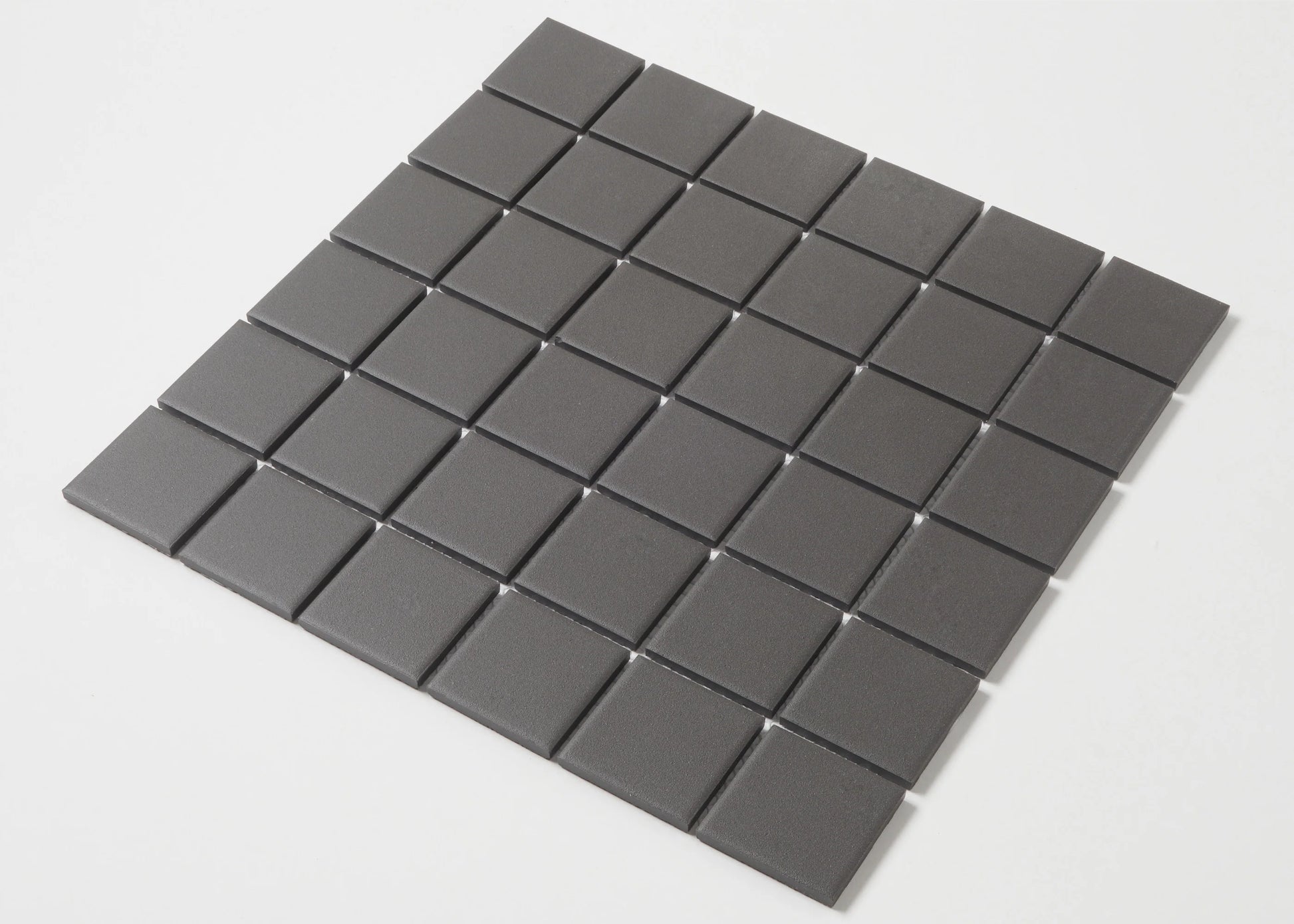 Pack shot of Marlowe Black Matt Mosaic 48x48mm showing a flat lay of uniform dark grey square tiles arranged in a grid pattern with fine grout lines.