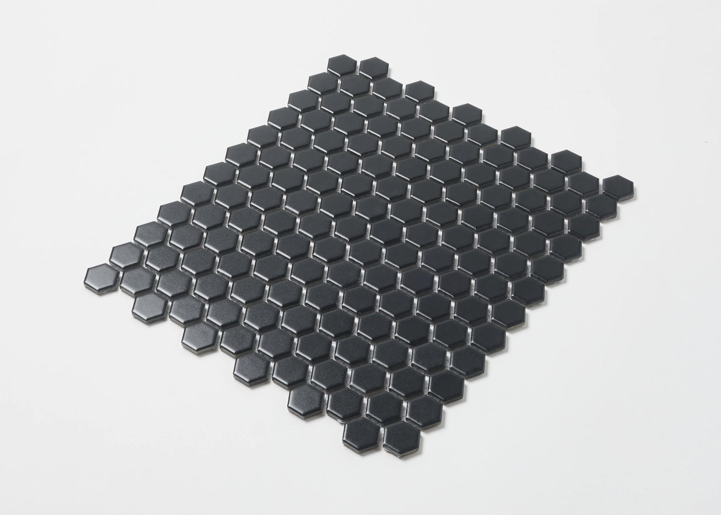 Pack shot of Marlowe Black Matt Mosaic Hexagon 23x23mm tiles arranged in a flat-lay sheet showing matte black hexagonal ceramic pieces with dark grout joints.