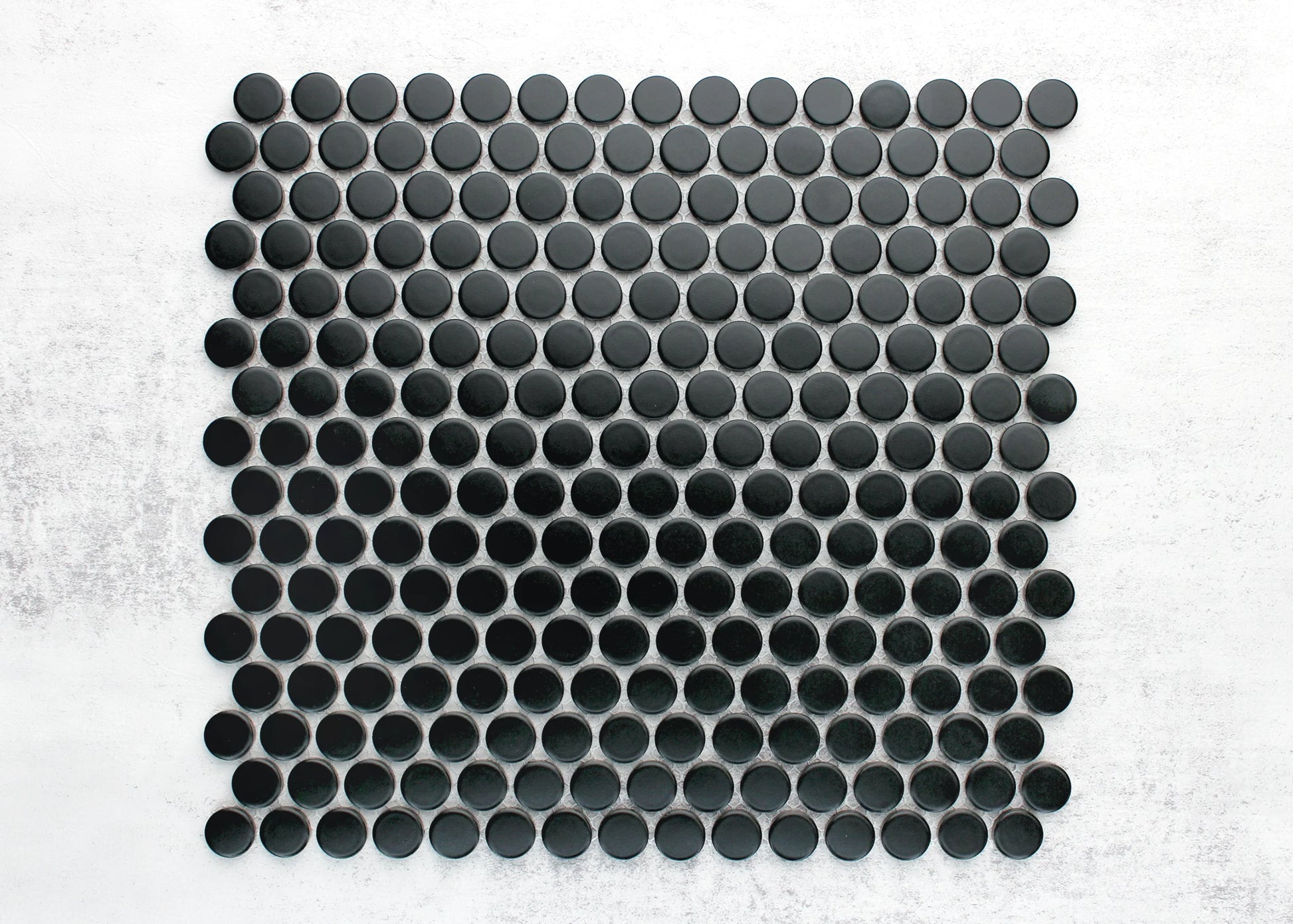 Overhead pack shot of Marlowe Black Matt Penny Round 19mm mosaic tile sheet showing uniform matte black circular tiles arranged in an offset grid pattern.