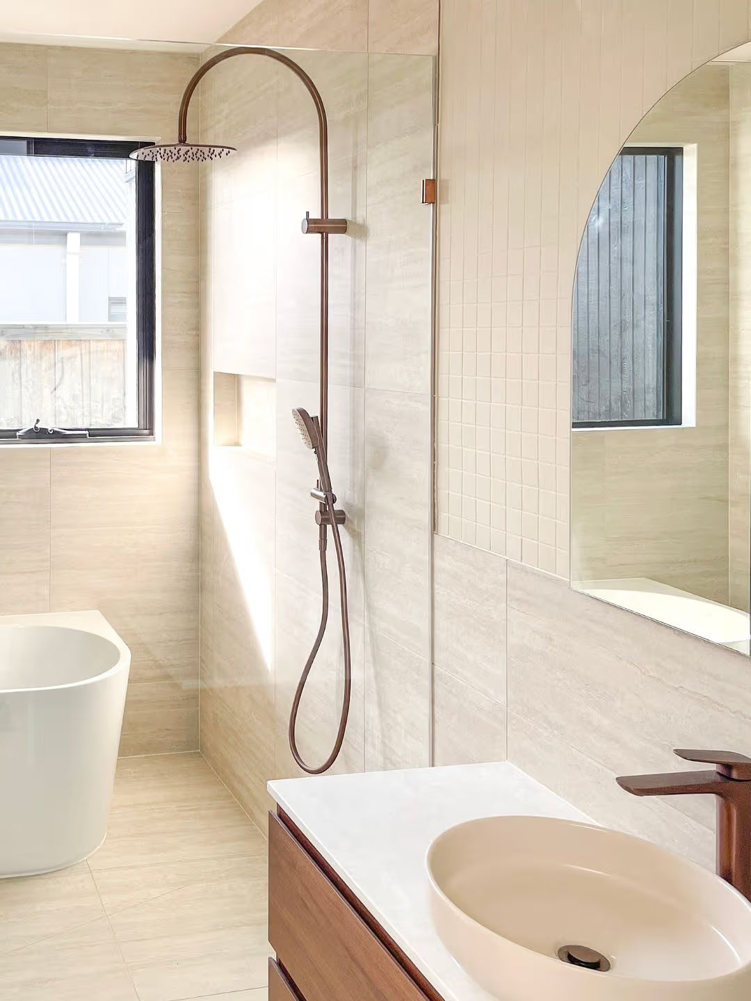 Marlowe Bone Matt Mosaic 48x48mm tiles installed on a shower feature wall alongside a timber vanity, vessel basin, and bronze rainfall shower fixtures.