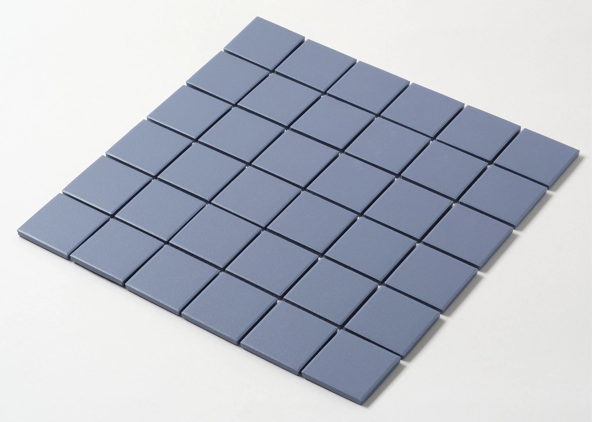 Pack shot of Marlowe Cornflower Blue Matt Mosaic 48×48 mm showing a flat grid of square matte blue-grey ceramic tiles with thin grout joints.