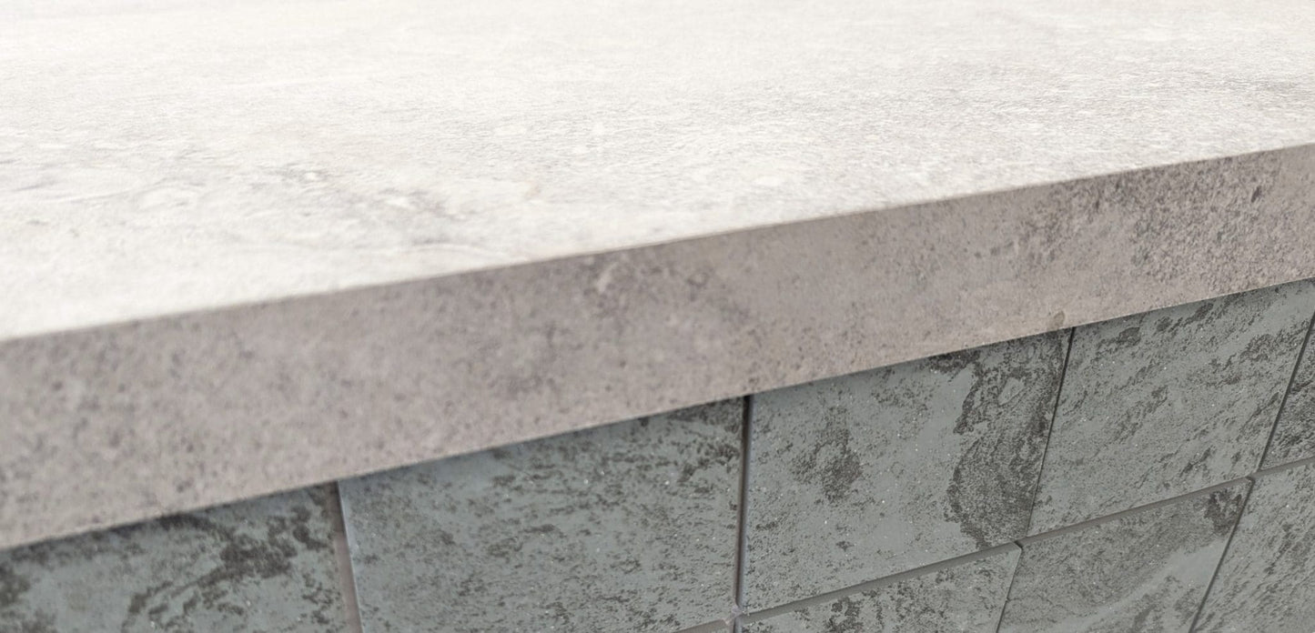 Mars Light External Pencil Bullnose 390.80x600x20mm shown as a light grey stone coping cap atop a dark grey textured tile wall, highlighting the bullnose edge profile.