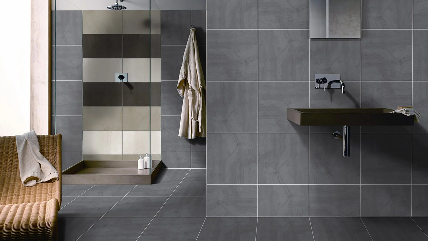Matang Charcoal Matt 400x400mm tiles covering the floor, walls, and walk-in shower of a contemporary bathroom with a wall-mounted vanity and woven bench seat.