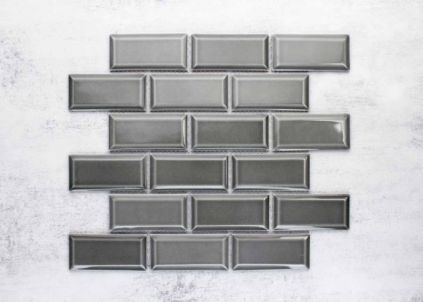 Medium Grey Gloss Glazed Porcelain Rectangle Bevelled Edge 45x95mm tiles arranged in a staggered brick pattern showing glossy finish and raised bevelled frame detail.