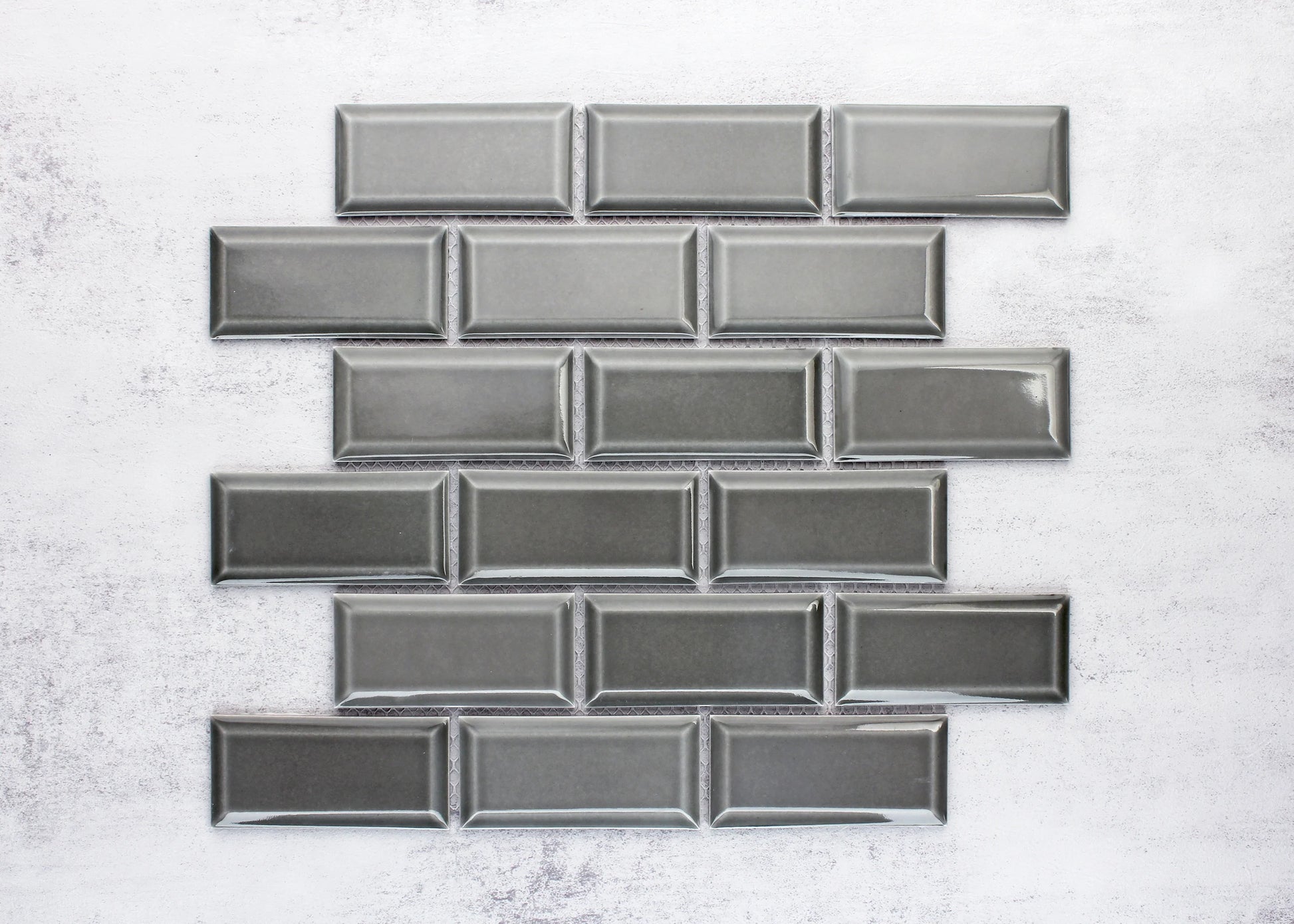 Medium Grey Gloss Glazed Porcelain Rectangle Bevelled Edge 45x95mm tiles arranged in a staggered brick pattern showing glossy finish and raised bevelled frame detail.