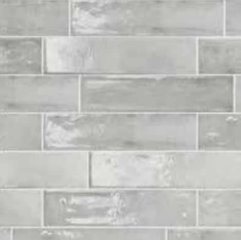 Close-up of Memory Pearl Grey Gloss 60x250mm wall tiles arranged in a brick-bond pattern with a subtle sheen and soft grey tonal variation.