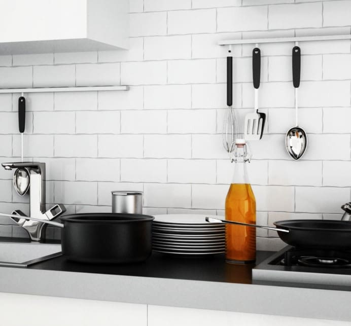 Metro White Gloss Subway Tile 75x300mm installed as a kitchen splashback behind black cookware, stacked plates, and hanging utensils on a rail.