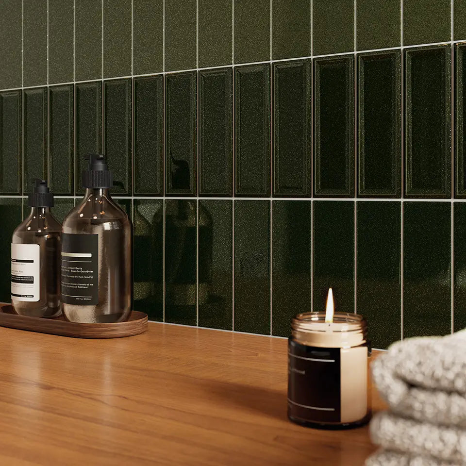 Micare Canale Evergreen Dark Gloss 50x150mm tiles installed as a bathroom vanity splashback, paired with a timber countertop, glass soap dispensers, and a lit candle.