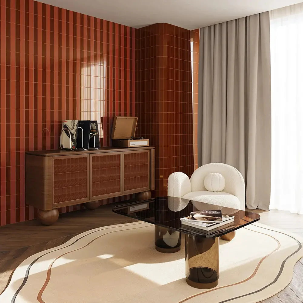 Micare Canale Saffron Dark Gloss 50x150mm tiles cover a warm terracotta feature wall in a stylish living room with a timber sideboard and white boucle armchair.