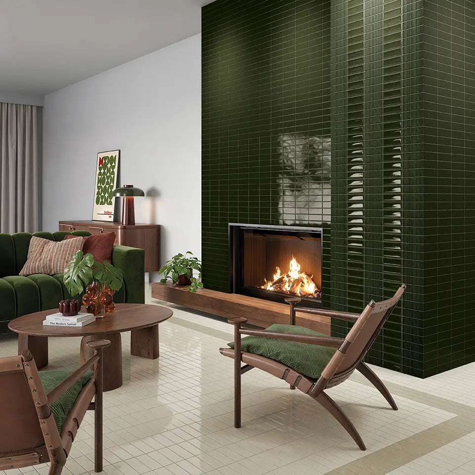 Micare Evergreen Dark Gloss 50x150mm tiles cladding a floor-to-ceiling fireplace feature wall in a mid-century living room with green velvet sofa and timber chairs.