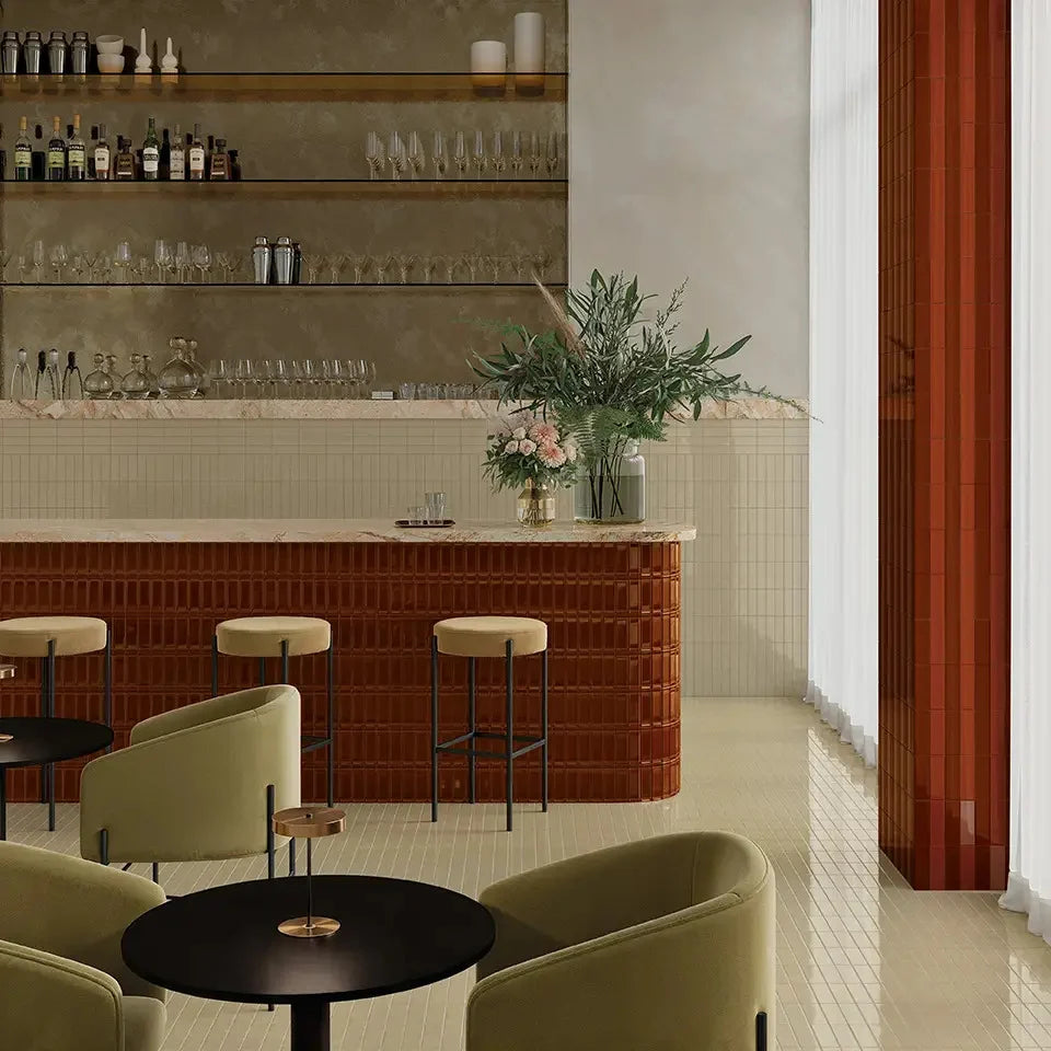Micare Linen Dark Gloss 50x150mm tiles clad across a curved bar counter in a sophisticated lounge interior with sage armchairs and marble countertop.